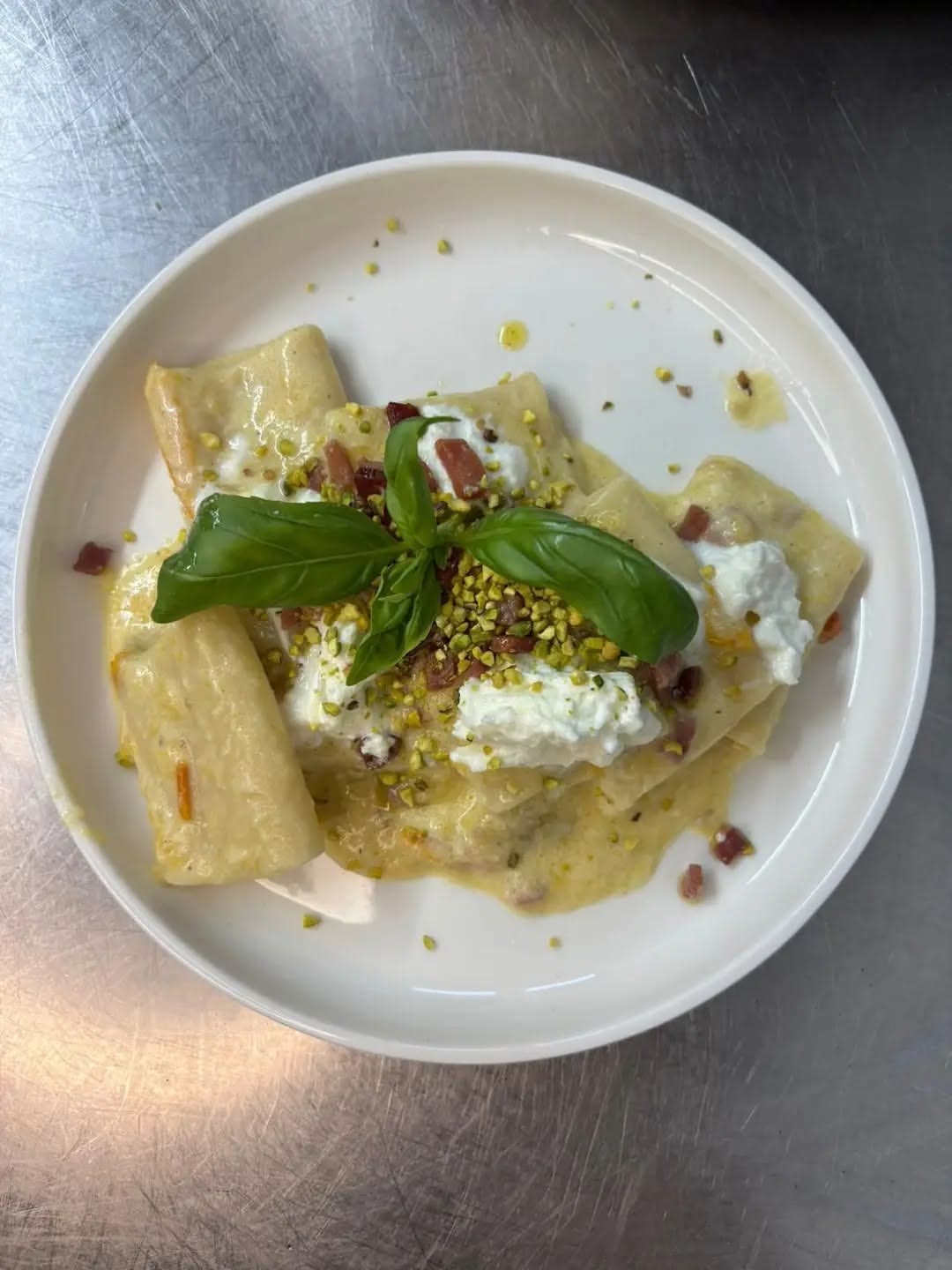 Primo piatto di pasta con crema, stracciatella, granella di pistacchio e basilico